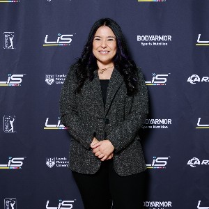 Professor wearing gray blazer against step and repeat at Latinos in Sports event